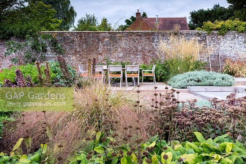 View across mixed border to outdoor table and chairs in contemporary country garden near Winchester, Hants, UK. Designed Elks-Smith Garden Design. 