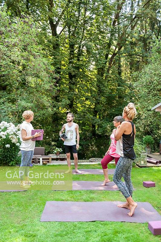 People talking after Yoga class in summer garden.