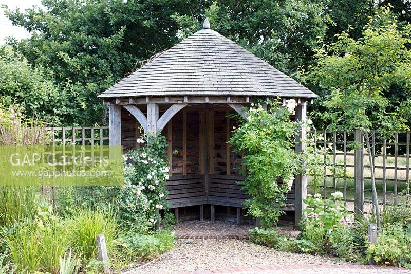 An oak timber garden arbour with oak benches and oak tiled roof. 