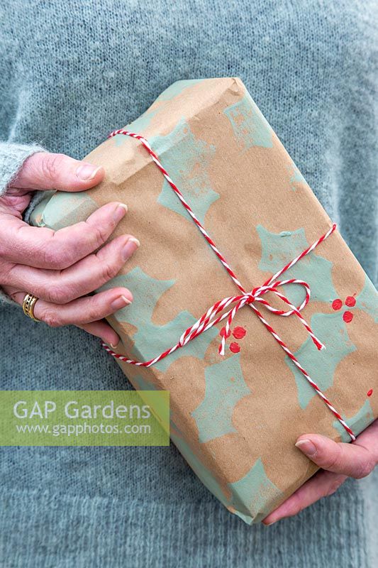 Woman holding christmas gift wrapped with handmade craft paper.