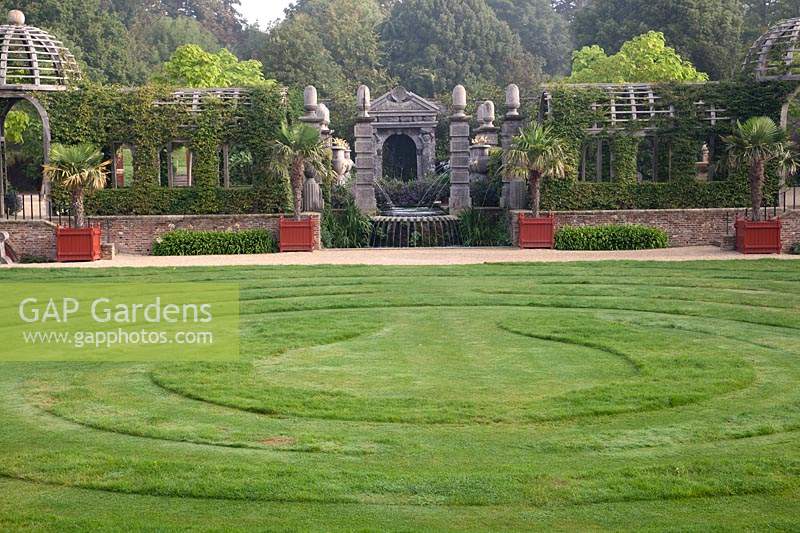 Mown grass labyrinth in the Collector Earl's Garden, with wooden arbour and columns. Arundel Castle, Sussex, UK.