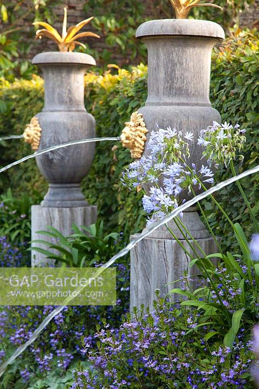 Italianate fountains in Collector Earl's garden, with flowering Agapanthus, Lobelia and Scaevola. Arundel Castle, Sussex, UK.