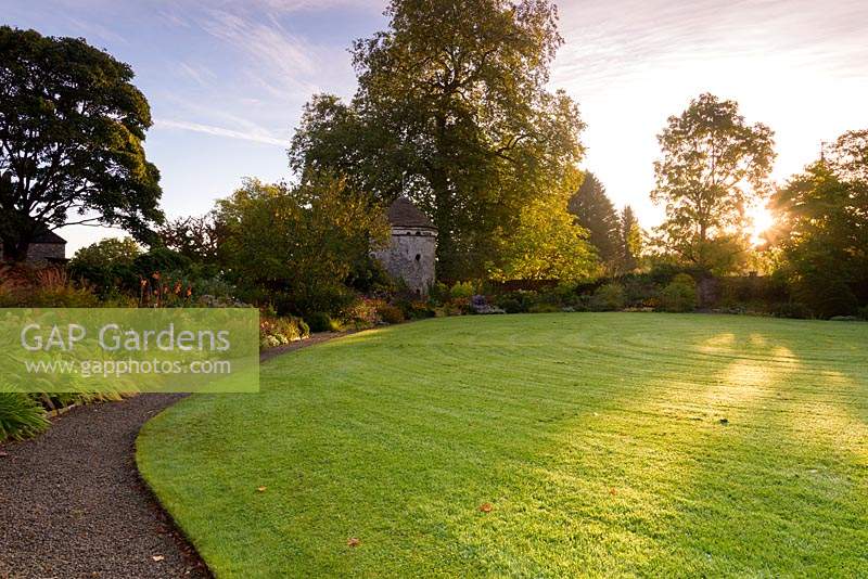 A deep border around the dovecote in the walled Round Garden. Llanover Gardens, Monmouthshire, UK. 