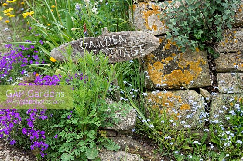 'Garden cottage'  wooden sign for a house near stone wall
