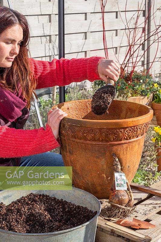 Woman adding gritty compost to large decorative container.