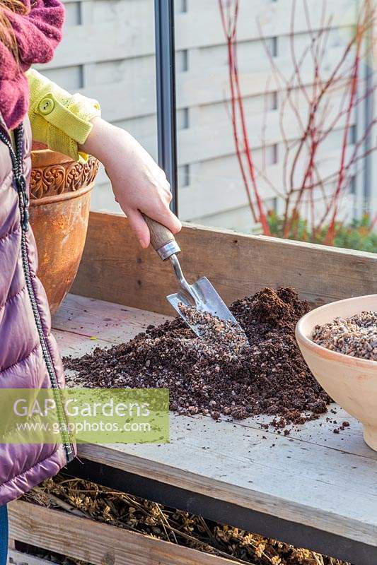 Woman adding horticultural grit to compost to make it free draining.
