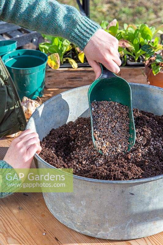 Woman adding horticultural grit into compost to make it free-draining.