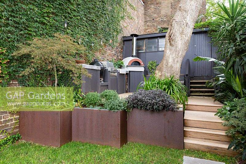 A  terrace edged with Cor-ten steel retaining wall and planters. 