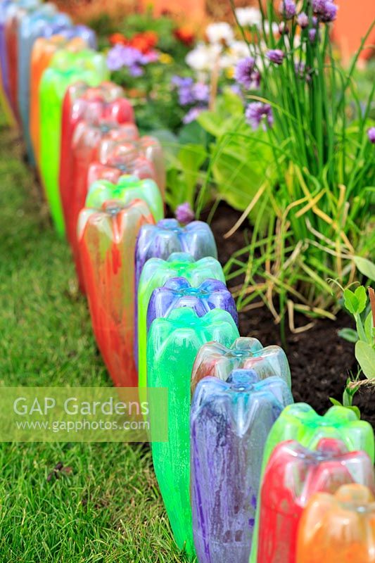 Painted upturned plastic bottles forming edging to bed of herbs