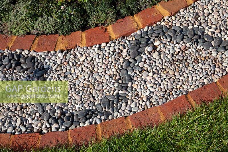 Brick edged sinuous path made from pebbles in the 'I Follow the Waters and the Wind' garden at RHS Malvern Spring Festival, 2017. 