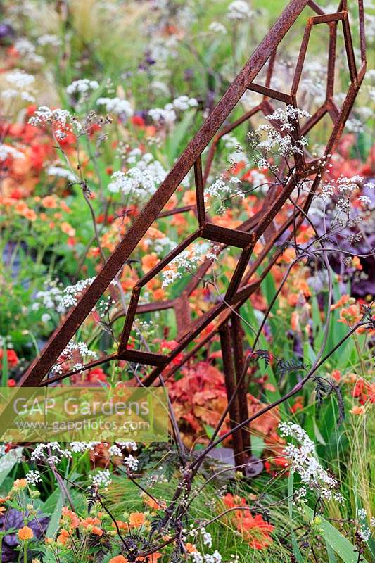 Detail of sculpture depicting a telescope surrounded by mixed planting. The Red Shift Garden, designed by Julie Bellingham. RHS Malvern Spring Festival, 2019. 
