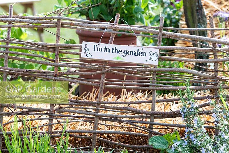 'Im in the garden' sign on a rustic fence
