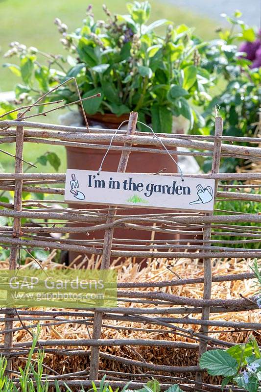 'I'm in the garden' sign on a rustic fence
