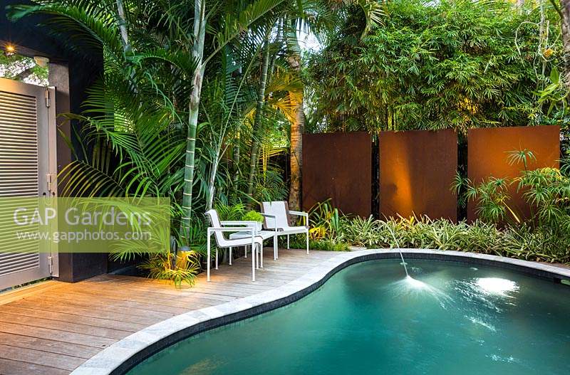 Small urban garden with plenty of privacy from walls, gates and tropical planting. Features include: swimming pool, deck and seating area.