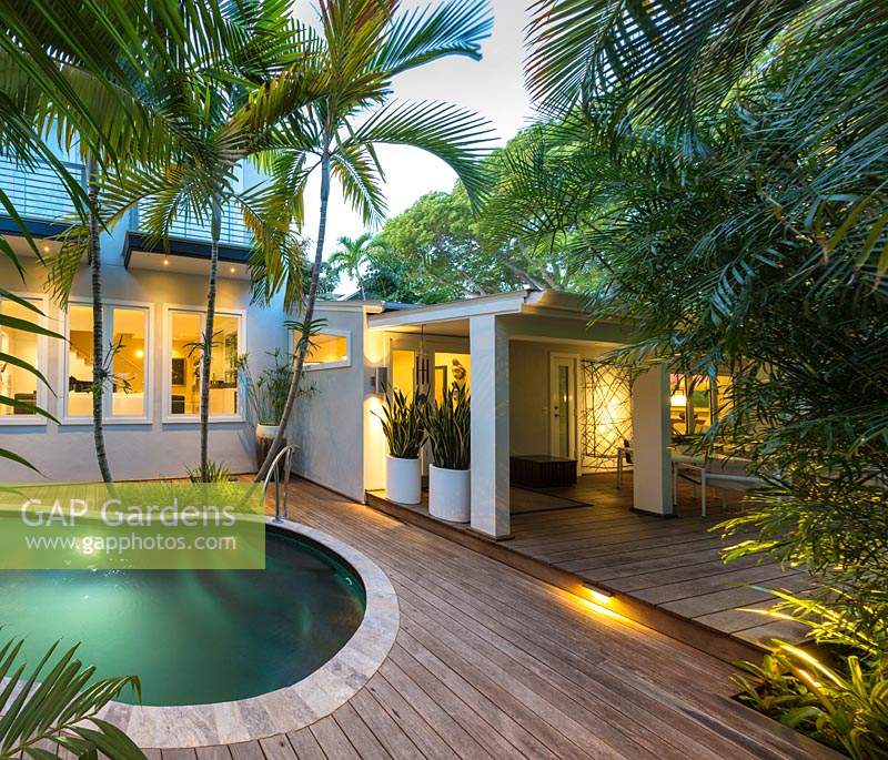 View of enclosed exotic garden, with wooden decking, palms and swimming pool. Von Phister Residence, Key West, Florida, USA. Garden design by Craig Reynolds.