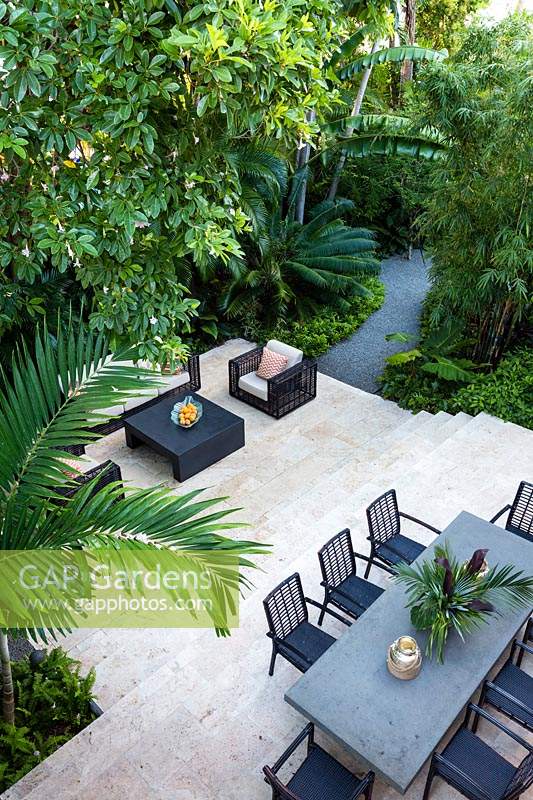 View across tropical, multi-level garden with modern furniture. Florida, USA. Garden design by Craig Reynolds Landscape Architecture.