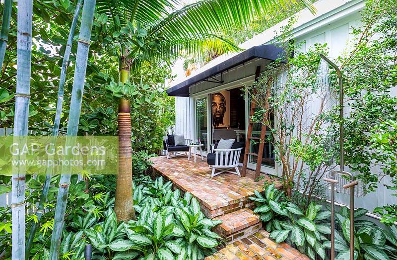 View of paved patio terrace with furniture in tropical garden. Key West Classic Garden, designed by Craig Reynolds. Key West, Florida, USA.
