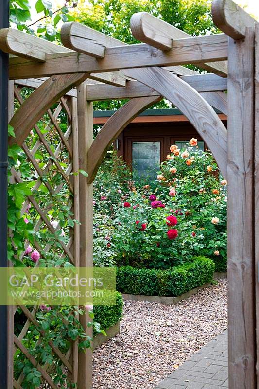 View through wooden arch to the Buxus-edged borders in the traditional rose garden, in garden of designer Karen Tatlow.
