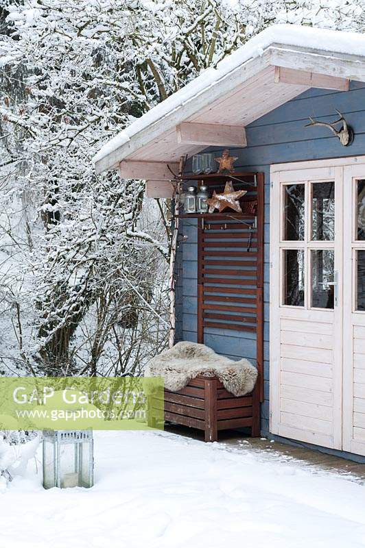 Blue, wooden summerhouse covered by snow in winter.