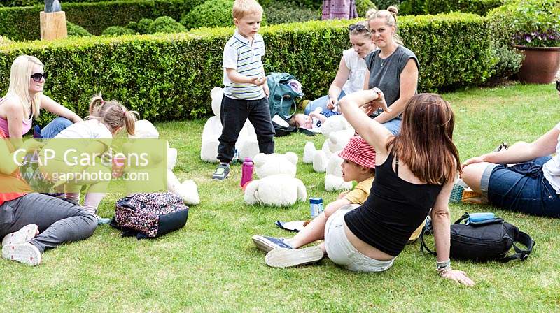 Teddy Bears Picnic - sculptures in Portland stone - on a lawn with children and parents interacting
