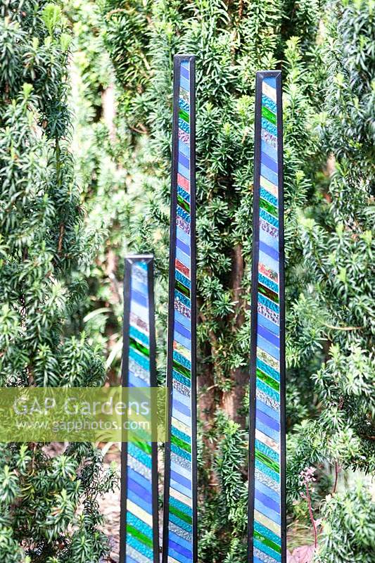 Blades - panels of glass and steel-- displayed amongst conifer foliage
