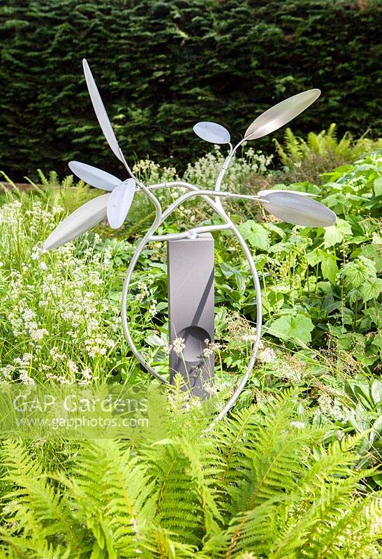 The Olive - artwork in aluminium and cement - set amongst green foliage
