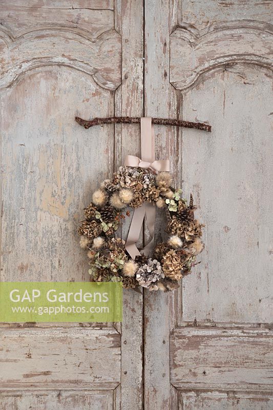 Wreath hung up on vintage French doors. Ingredients include: 
Hydrangea, Rosa - Rosehip, seedhead, Pine cone and Pheasant feather.
