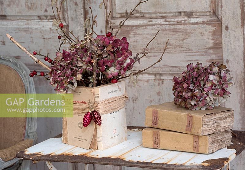 Dried red Hydrangea flowerheads and twigs with vintage books
