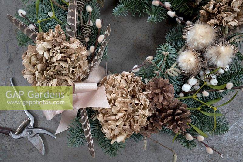 Close up of wreath with dried Hydrangea flower, pine cones, mistletoe, 
snowberries, pussy willow, pheasant feathers and seed heads