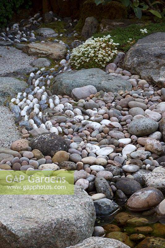 River pattern with pebbles in Japanese-themed garden.
