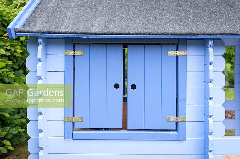 Window of a Blue painted children's playhouse in garden. 