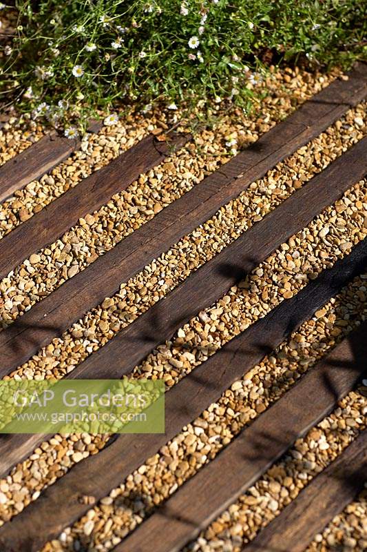Detail of wood and gravel path area.  Southend Young Offenders 'A Place to Think' garden, designed by James Callicott and Tony Wagstaf, sponsored by Southend Council, Sovereign Play Equipment, Stephanie Cushing - Sculpture. RHS Hampton Court Palace Show, 2018. 
