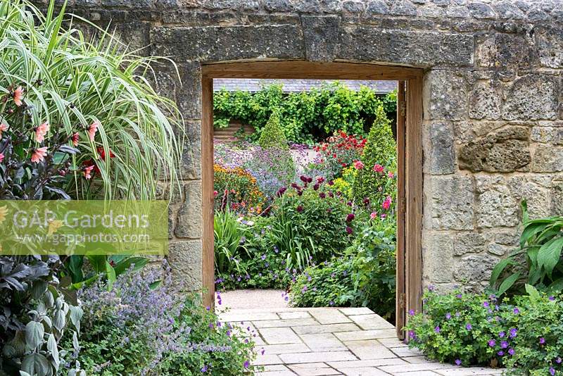 A doorway in an ancient stone wall opens to reveal the walled kitchen garden beyond.