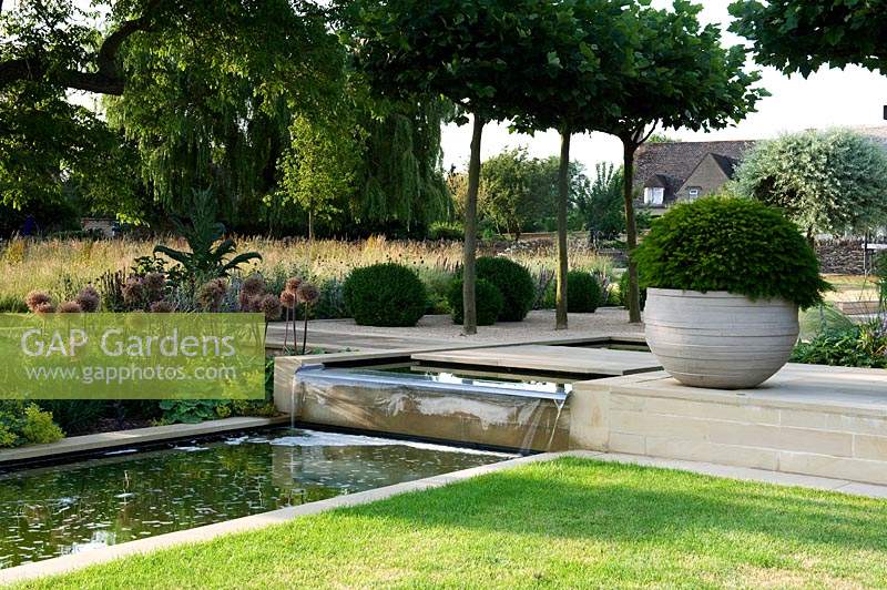 Modern water feature, waterfall and pool in contemporary garden. 
