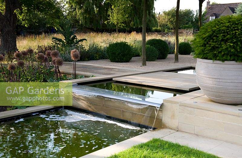 Modern water feature, waterfall and pool in contemporary garden.

