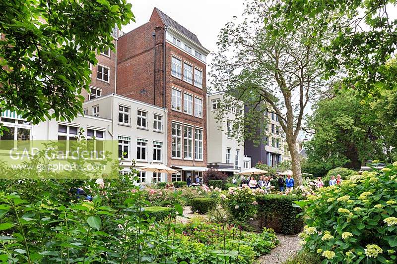 The communal garden at De Bary, Amsterdam, The Netherlands, designed by Cilia Prenen. View to the apartments facing the garden, from one end, with visitors enjoying the garden. 