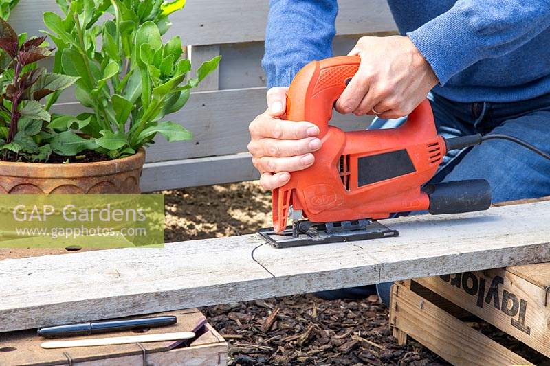 Woman using a jigsaw to cut hole in gravelboard following the marked out shape