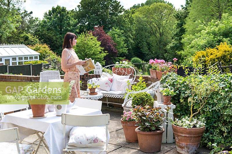 Woman on patio surrounded by large terracotta containers with cottage style planting