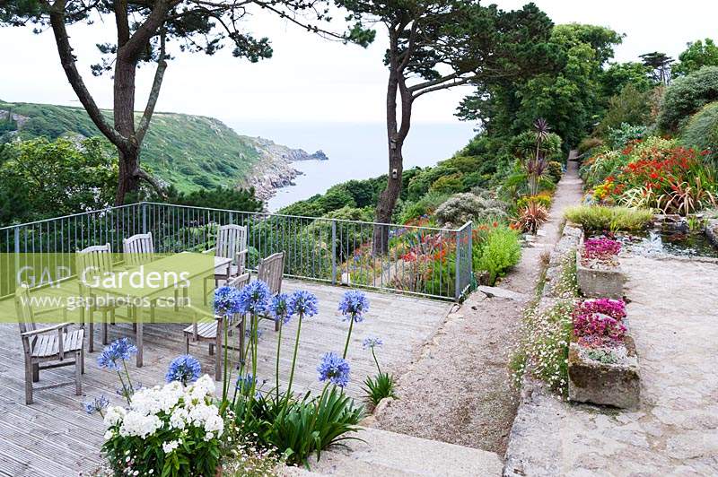 View from the terrace across the garden to Lamorna Cove and the sea beyond, framed by Scots Pines. 