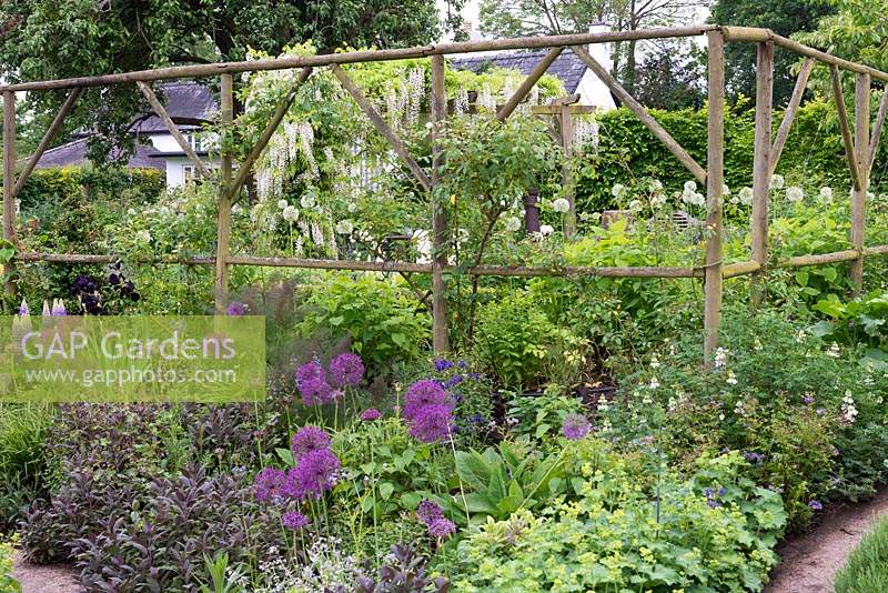 Mixed perennial border with rustic wooden screen. 
