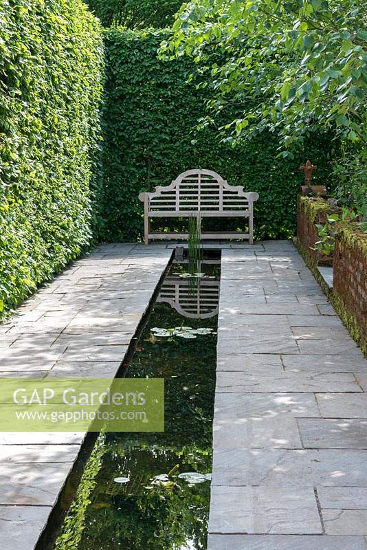 A tranquil rill measuring 14m long set in stone paving, overlooked by a Lutyens style bench.
