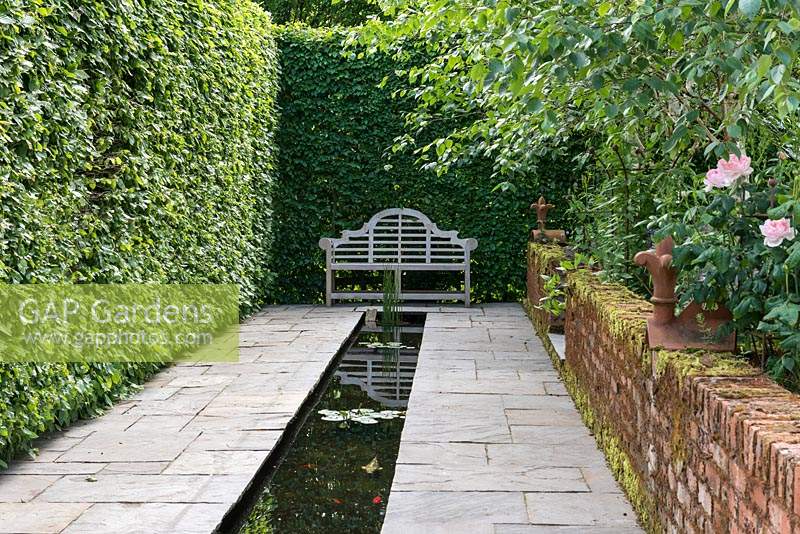 A tranquil rill measuring 14m long set in stone paving, overlooked by a Lutyens style bench.