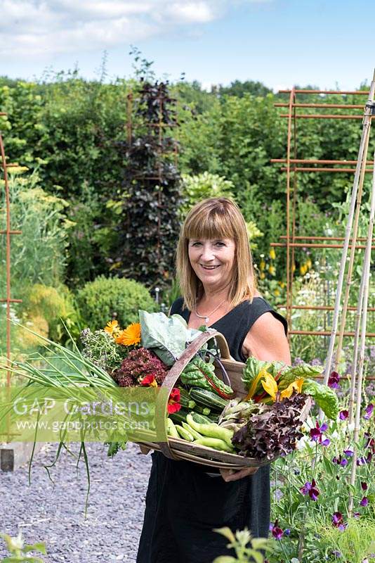 Alison Szafranski with a trug of freshly picked vegetables and edible flowers picked from her kitchen garden.