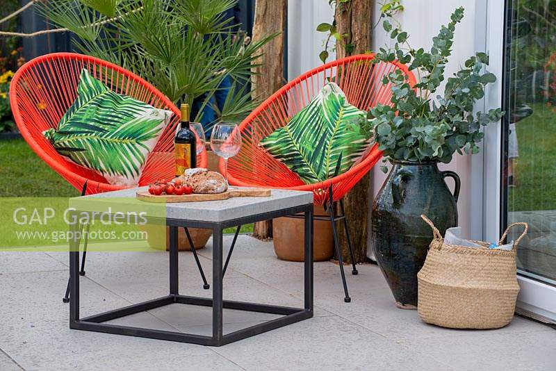 Contemporary table and chairs on a patio, branches of Eucalyptus in a jar - Mediterranean Terrace - Green Living Spaces, RHS Malvern Spring Festival 2019