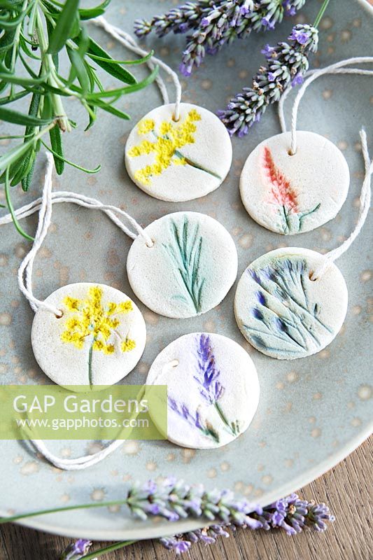 Decorated salt dough tiles with string for hanging arranged on a plate.