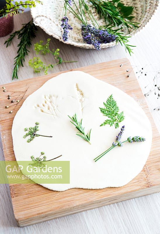 Roll out the salt dough on to a lightly floured surface to a thickness of approx 5mm. Arrange flowers and leaves on to rolled out dough, leaving enough space around each one to cut out