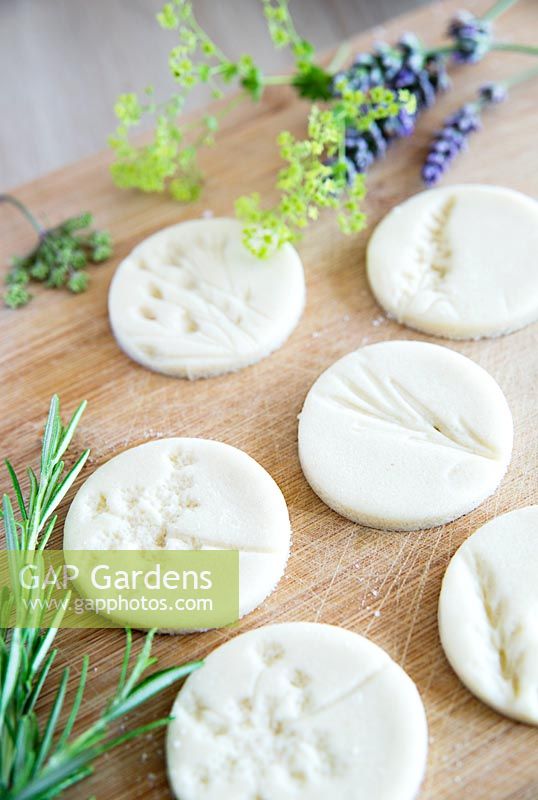 Circular discs of salt dough with impressions left by flowers to make gift tags
