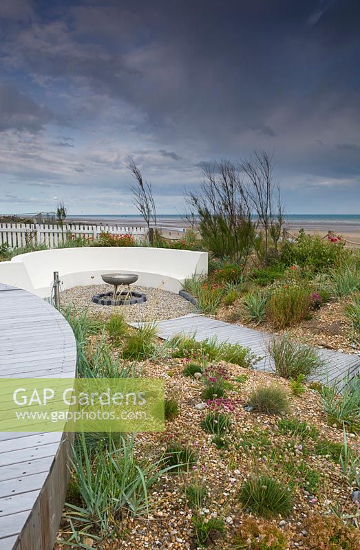 Modern, landscaped seaside garden, with curved bench and gravel borders.