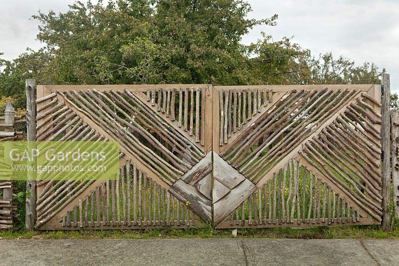 Wooden gate made with branches opening into orchard - Chile