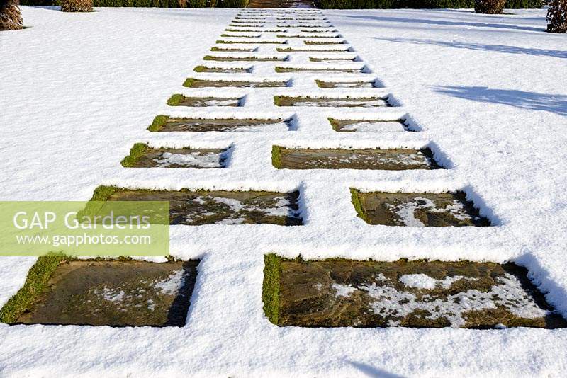 Stone paving across the lawn with snow in January.